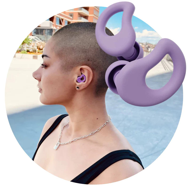 Purple CURVD earplugs in front of attractive young woman wearing CURVD ultra-soft, comfortable, low-profile and stylish purple CURVD earplugs