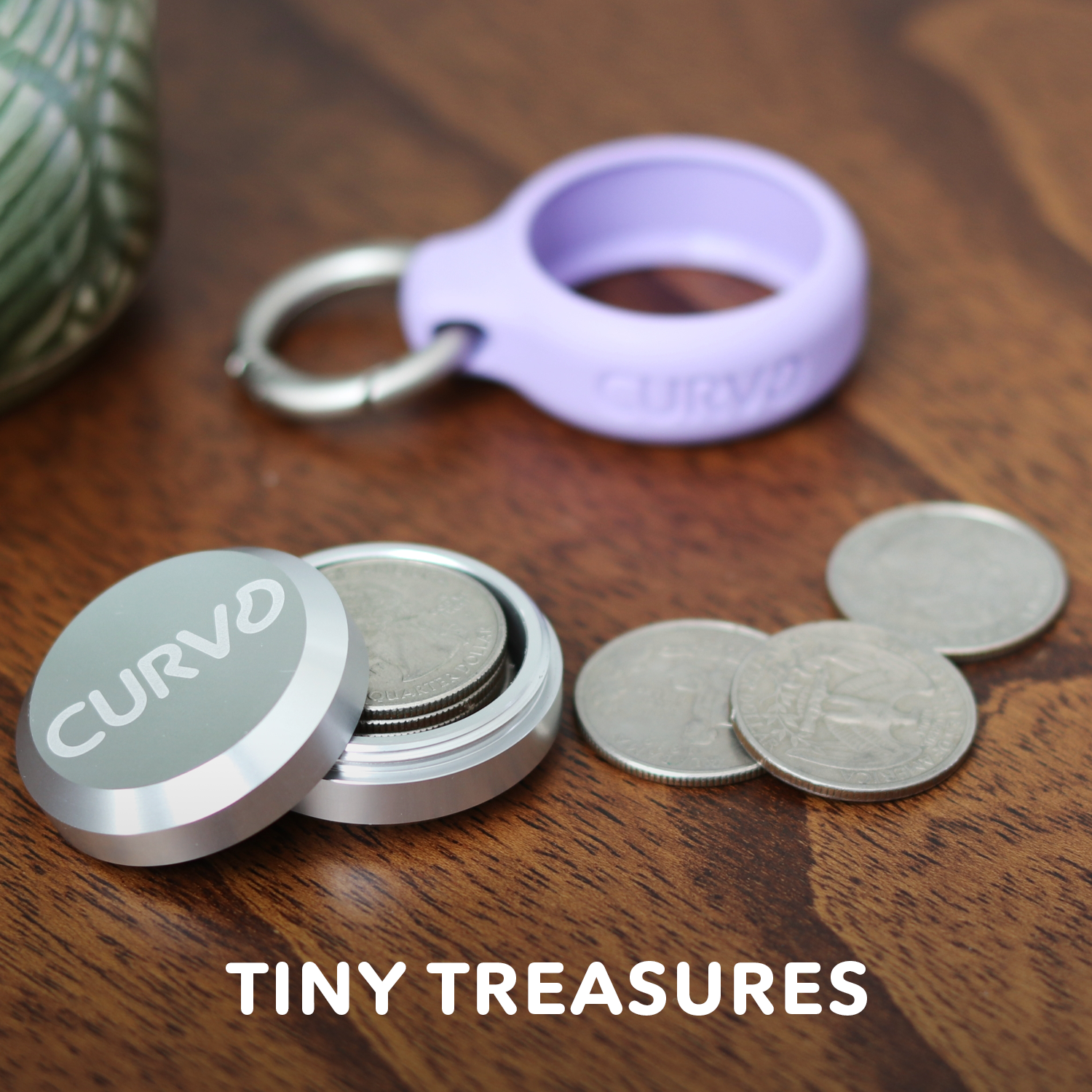 A small round metal container with the word "CURV3" on the lid is open, revealing coins inside. Next to it are a few coins and a purple ring with "CURV3" inscribed, all on a wooden surface. The **Premium Carrying Case Plus Clip** sits beside them. The text **"TINY TREASURES"** from **CURVD Earplugs** is at the bottom of the image.