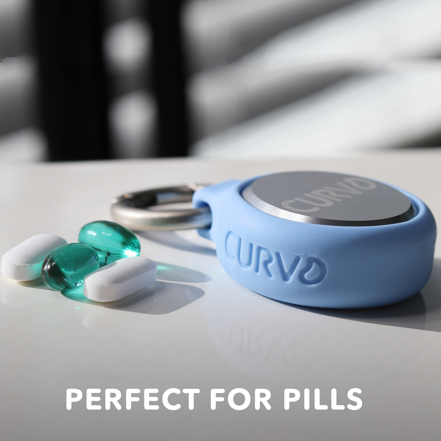 A Premium Carrying Case Plus Clip by CURVD Earplugs is shown on a white surface. Next to it are two green translucent capsules and two white tablets. The text "PERFECT FOR PILLS" is displayed at the bottom of the image, highlighting its use as a premium carrying case perfect for daily medication needs.